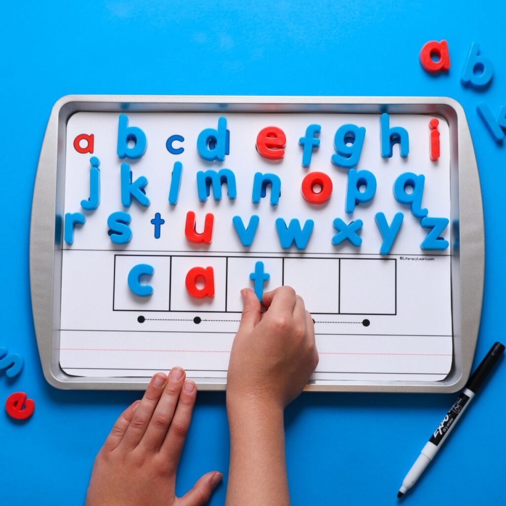 A child using a magnet letter board to build the word "cat."